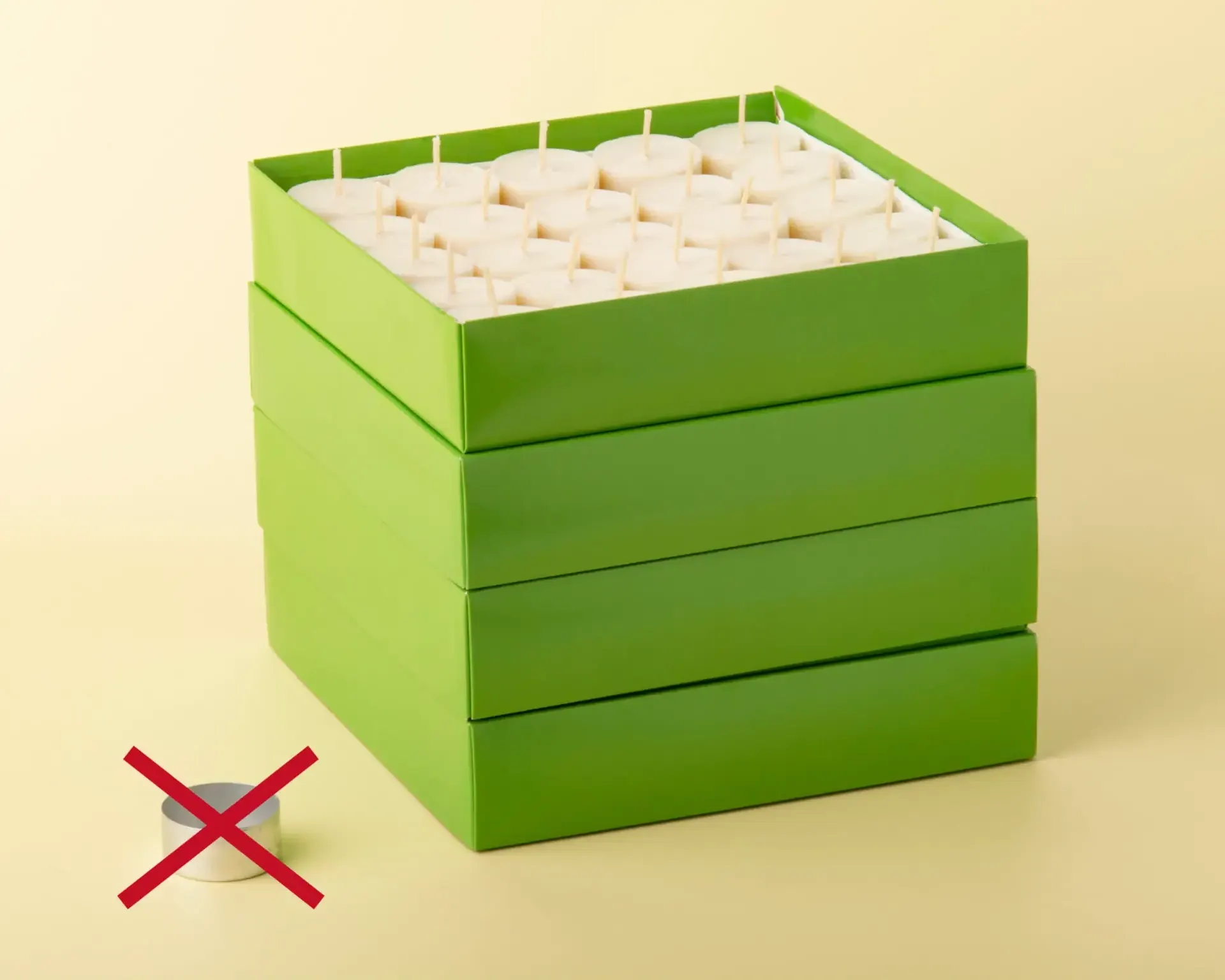 Gestapelte grüne Kartons mit 200 Grüne-Lichter-Teelichtern, daneben eine durchgestrichene Aluminiumschale
