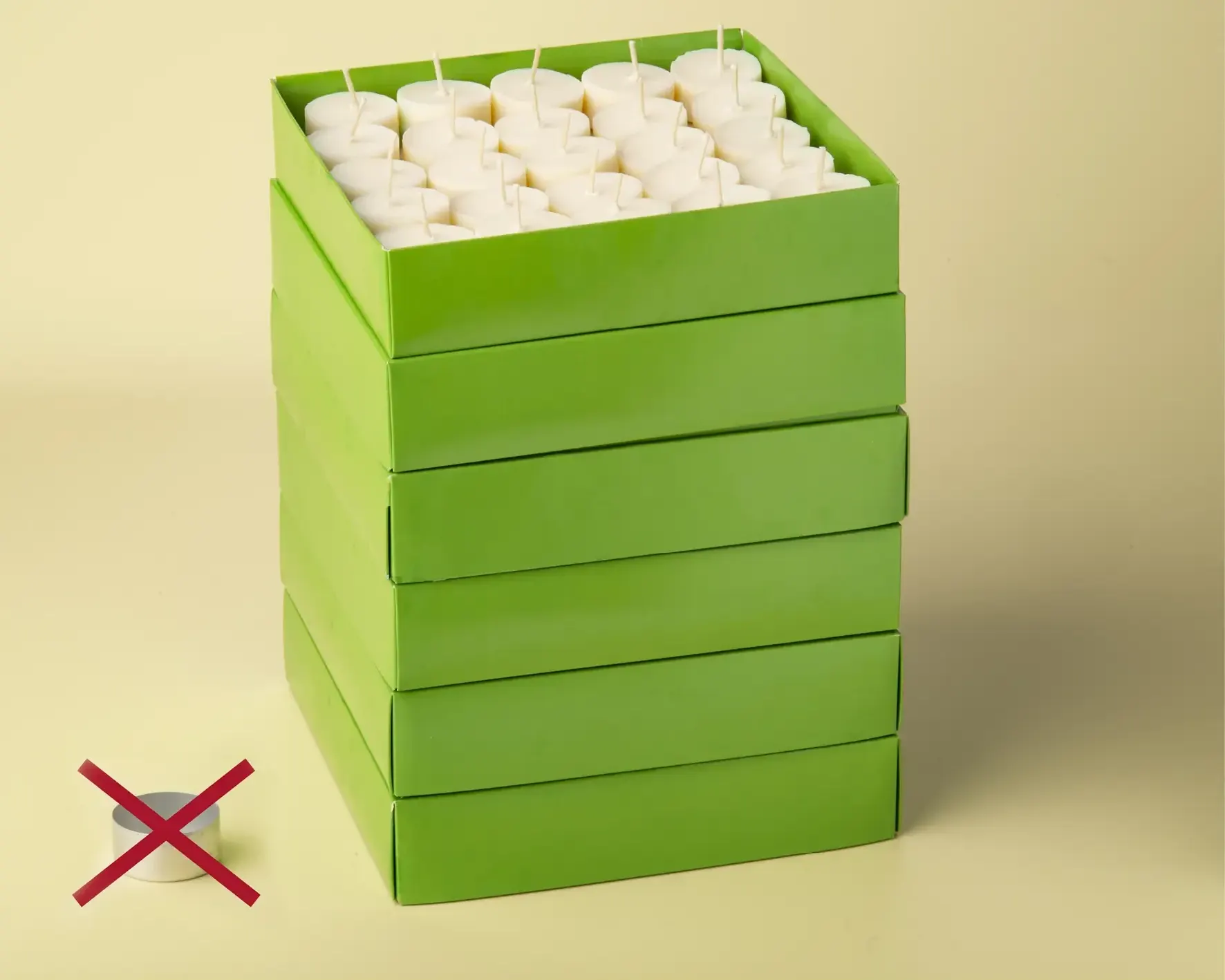 Gestapelte grüne Kartons mit 300 Grüne-Lichter-Teelichtern, daneben eine durchgestrichene Aluminiumschale